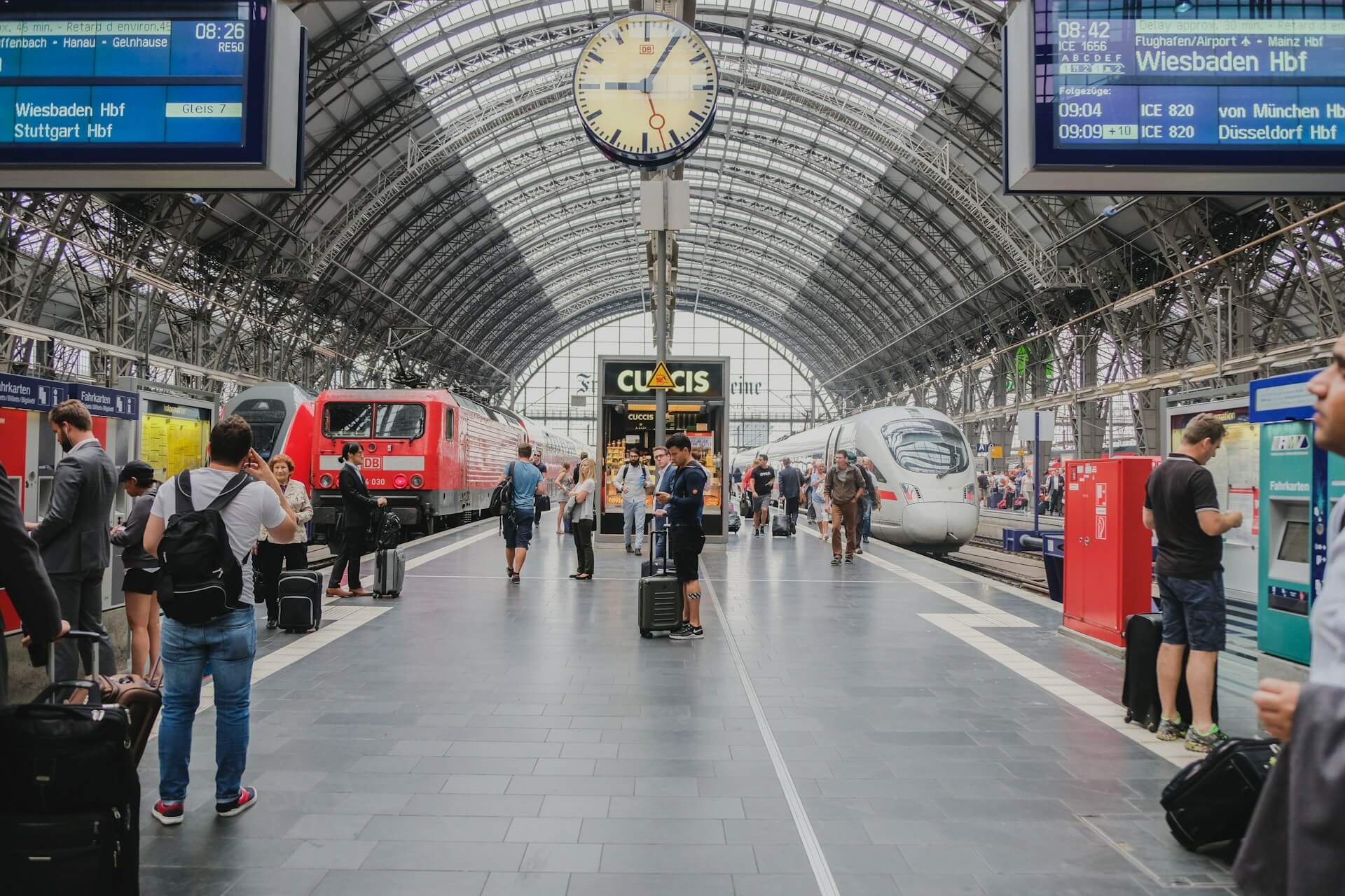 People waiting to meet friends under a clock in a busy train station